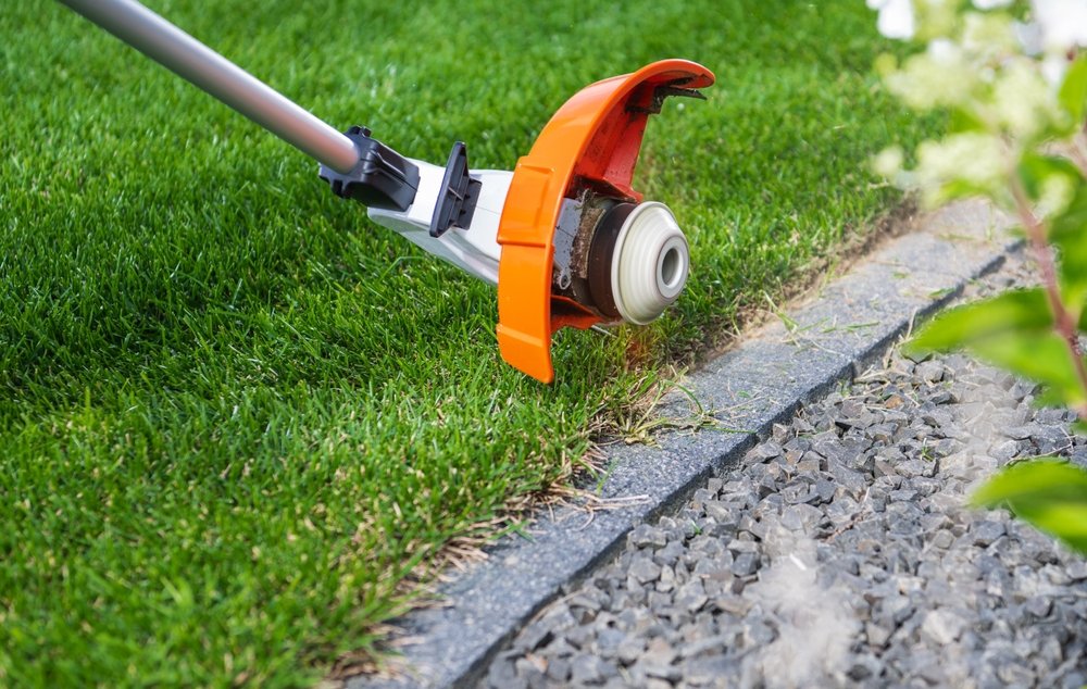 A,person,trims,the,grass,close,to,a,stone,edge
